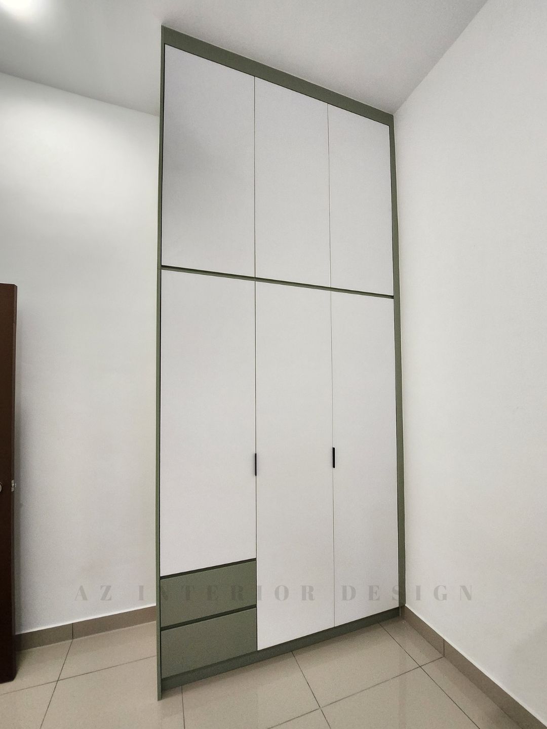 Close-up of a European-style wardrobe featuring olive green-gray panels, white doors, and visible modern handles